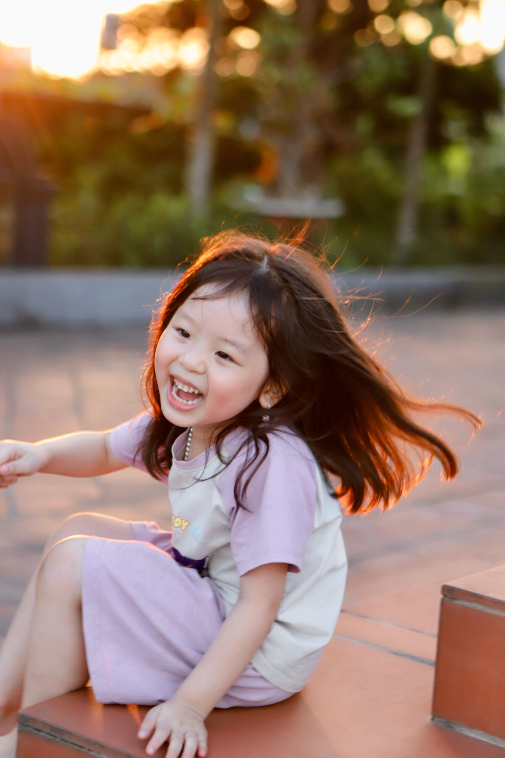 Adorable Vietnamese child joyfully playing outdoors in Hai Duong at sunset, capturing a moment of carefree happiness.